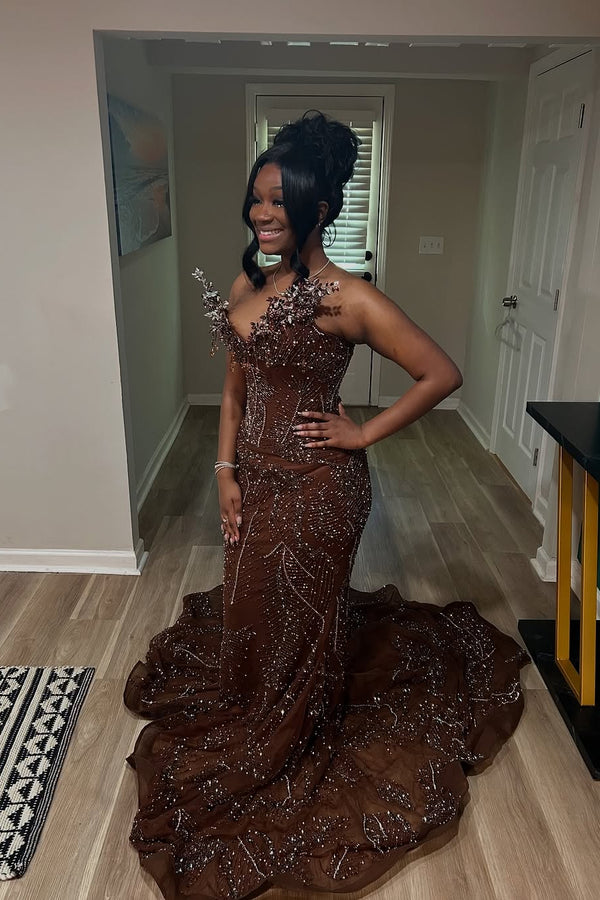 Woman in a brown beaded evening gown standing in a room.