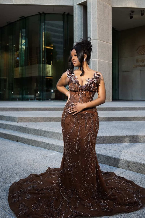 Woman in a brown beaded evening gown standing on steps in front of a building.